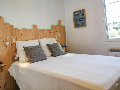 a bedroom with a large bed with a wooden headboard at Balcis Apartment by Hello Homes Sitges in Sitges