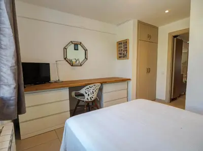 a bedroom with a bed and a desk with a mirror at Balcis Apartment by Hello Homes Sitges in Sitges