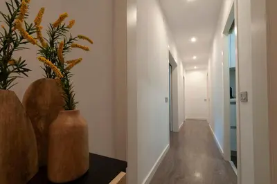 a hallway with white walls and a vase with flowers at Opening Doors Poblenou Beach in Barcelona