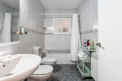 a white bathroom with two toilets and a sink at Casa de vacances Mary in Santa Eulalia de Ronsaná