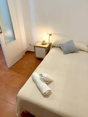 a bedroom with a white bed and a night stand at Apartamento St Agustí - Centric in Mataró