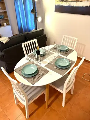 a dining room table with four chairs and a table with plates and glasses at Apartamento St Agustí - Centric in Mataró