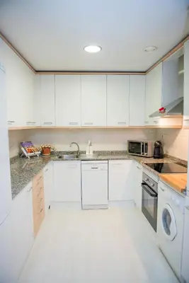 a white kitchen with white cabinets and a dishwasher at Opening Doors Pueblonuevo in Barcelona