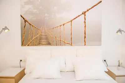 a suspension bridge painting hangs above a white couch at Opening Doors Pueblonuevo in Barcelona