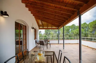 an outdoor patio with a glass table and chairs at Casa Fontanals in Pla del Panadés