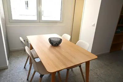 a wooden table with white chairs and a bowl on it at Homenfun Barcelona Hospital Clínic l in Barcelona