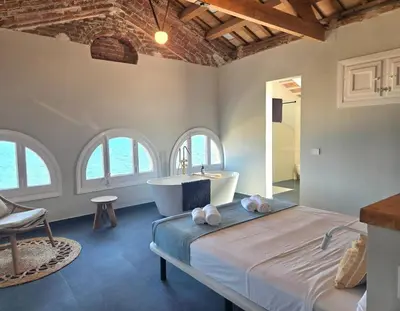 a bedroom with a bed and a tub and windows at Casa Mas Blau | Increíbles vistas frente al mar in San Pol de Mar