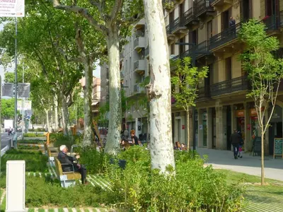 a man sitting on a bench in front of a building at Barcelona Classic Eixample Apartments in Barcelona