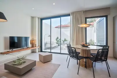 a living room with a table and chairs and a television at Sitges Spaces Garden Condo-2 Bedrooms, 2 Bathrooms, Garden Terrace, Near center, Sleeps up to 6- Monthly Rentals Only in Sitges
