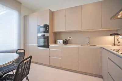 a kitchen with white cabinets and a table with chairs at Sitges Spaces Garden Condo-2 Bedrooms, 2 Bathrooms, Garden Terrace, Near center, Sleeps up to 6- Monthly Rentals Only in Sitges
