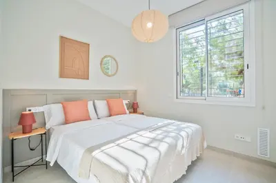a white bedroom with a bed and a window at Sitges Spaces Garden Condo-2 Bedrooms, 2 Bathrooms, Garden Terrace, Near center, Sleeps up to 6- Monthly Rentals Only in Sitges