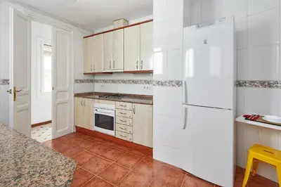 a kitchen with white cabinets and a white refrigerator at Gran Via - 1 in Barcelona