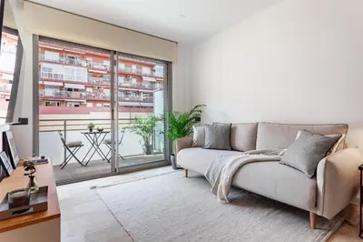 a living room with a couch and a large window at Cozy Apartment II - Les Corts in Barcelona