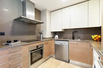 a kitchen with white cabinets and stainless steel appliances at Cozy Apartment II - Les Corts in Barcelona