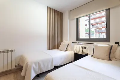 a hotel room with two beds and a window at Cozy Apartment II - Les Corts in Barcelona