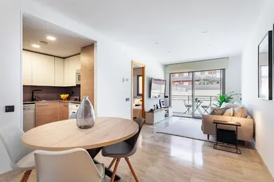 a kitchen and living room with a table and chairs at Cozy Apartment II - Les Corts in Barcelona