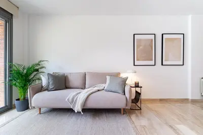 a couch in a living room with two pictures on the wall at Cozy Apartment II - Les Corts in Barcelona