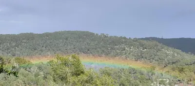 a rainbow on the side of a mountain at Ànima del Garraf in Sitges