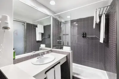 a white bathroom with a sink and a mirror at Alexandre FrontAir Congress in Sant Boi del Llobregat