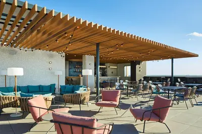 a patio with chairs and tables under a wooden pergola at Four Points by Sheraton Barcelona Airport in Barcelona