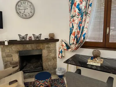 a living room with a fireplace and a clock on the wall at Hidden Garden Haven for 7 People in Vallromanas