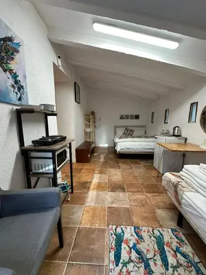 a living room with two beds and a couch at Hidden Garden Haven for 7 People in Vallromanas