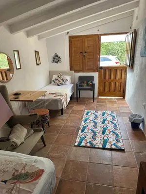 a room with two beds and a table and a rug at Hidden Garden Haven for 7 People in Vallromanas