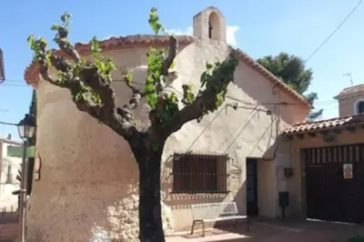 a tree in front of a house with a building at Alt Penedes, terra de vinya, sol, aigua i muntanya in Torrellas de Foix