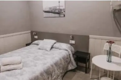 a small bedroom with a bed and a table at Pensión 45 in Barcelona