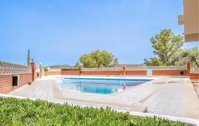 a swimming pool with a fountain and a brick wall at Amazing Apartment In Sant Pere De Ribes in Sant Pere de Ribes