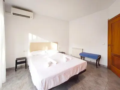 a bedroom with a large white bed and a chair at Casa en alquiler vacacional Vilanova i la Geltrú in Vilanova i la Geltrú