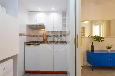 a kitchen with white cabinets and a blue table at Alojamiento en el barrio de gracia in Barcelona