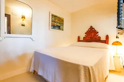 a white bedroom with a bed and a mirror at Infinity Jupi Sea in Sitges