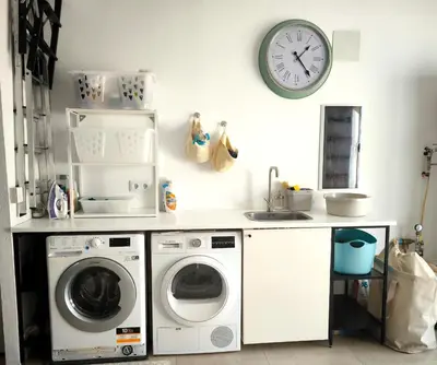 a kitchen with a washing machine and a clock on the wall at Casa Blanca in Sant Cebrià de Vallalta
