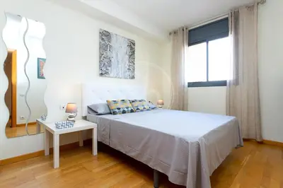 a bedroom with a bed and a table and a window at Cómodo apartamento junto a Hospital Sant Pau in Barcelona
