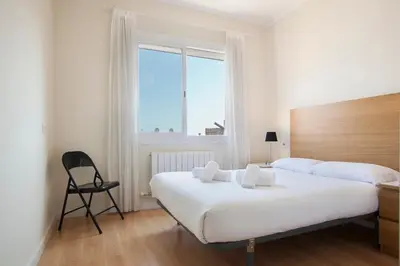 a hotel room with two beds and a chair at BBarcelona Aragó Flat in Barcelona