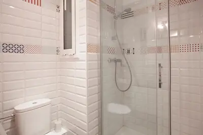 a white bathroom with a shower and a toilet at BBarcelona Aragó Flat in Barcelona
