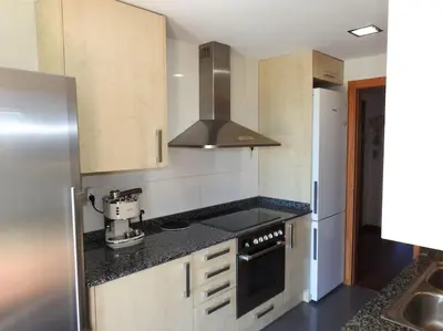 a kitchen with a stove top oven next to a refrigerator at Piso en zona fòrum con vistas al mar in Barcelona