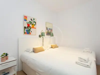 a bedroom with a white bed with a mirror at Agradable y luminoso apartamento ideal para 5 in Barcelona