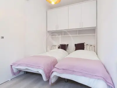 two beds in a white room with pink and white sheets at Apartamento Luminoso cerca de Montjuïc in Barcelona