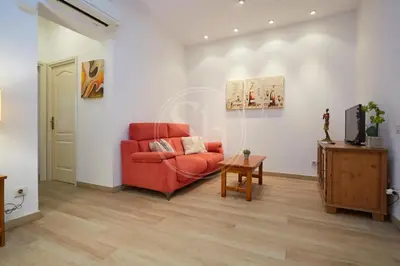 a living room with a red chair and a tv at Bonito apartamento cerca de Plaza España in Barcelona