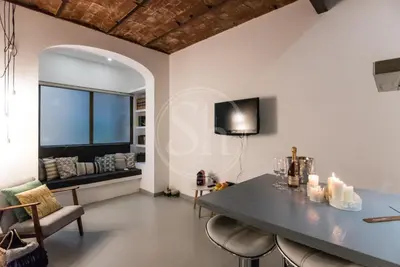 a living room with a table and chairs and a tv at Acogedor apartamento en el Eixample in Barcelona