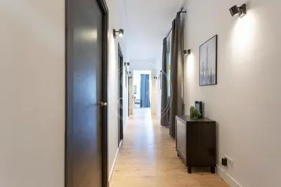 a hallway with a black door and a wooden floor at Céntrico apartamento familiar in Barcelona