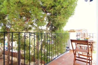 a balcony with a fence and a table and a tree at Mediterrani Vacaciones perfectas y vistas al mar in Sitges