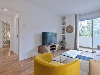 a living room with a yellow chair and a tv at Alcam Espronceda in Barcelona