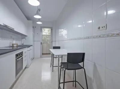 a white kitchen with a table and chairs in it at Alcam Espronceda in Barcelona