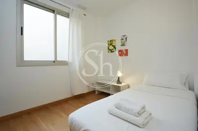 a white bedroom with a bed and a window at Bonito alojamiento cerca de Estación de Sants in Barcelona