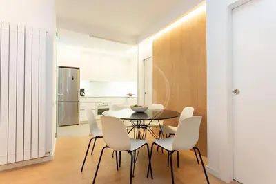 a dining room with a table and white chairs at Apartamento Familiar junto a Hospital Clinic in Barcelona