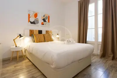 a kitchen with wooden cabinets and a white dishwasher at Apartamento cerca de Sagrada Familia in Barcelona