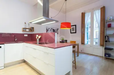 a kitchen with white cabinets and a red counter top at Bonito apartamento en La Rambla del Poblenou in Barcelona